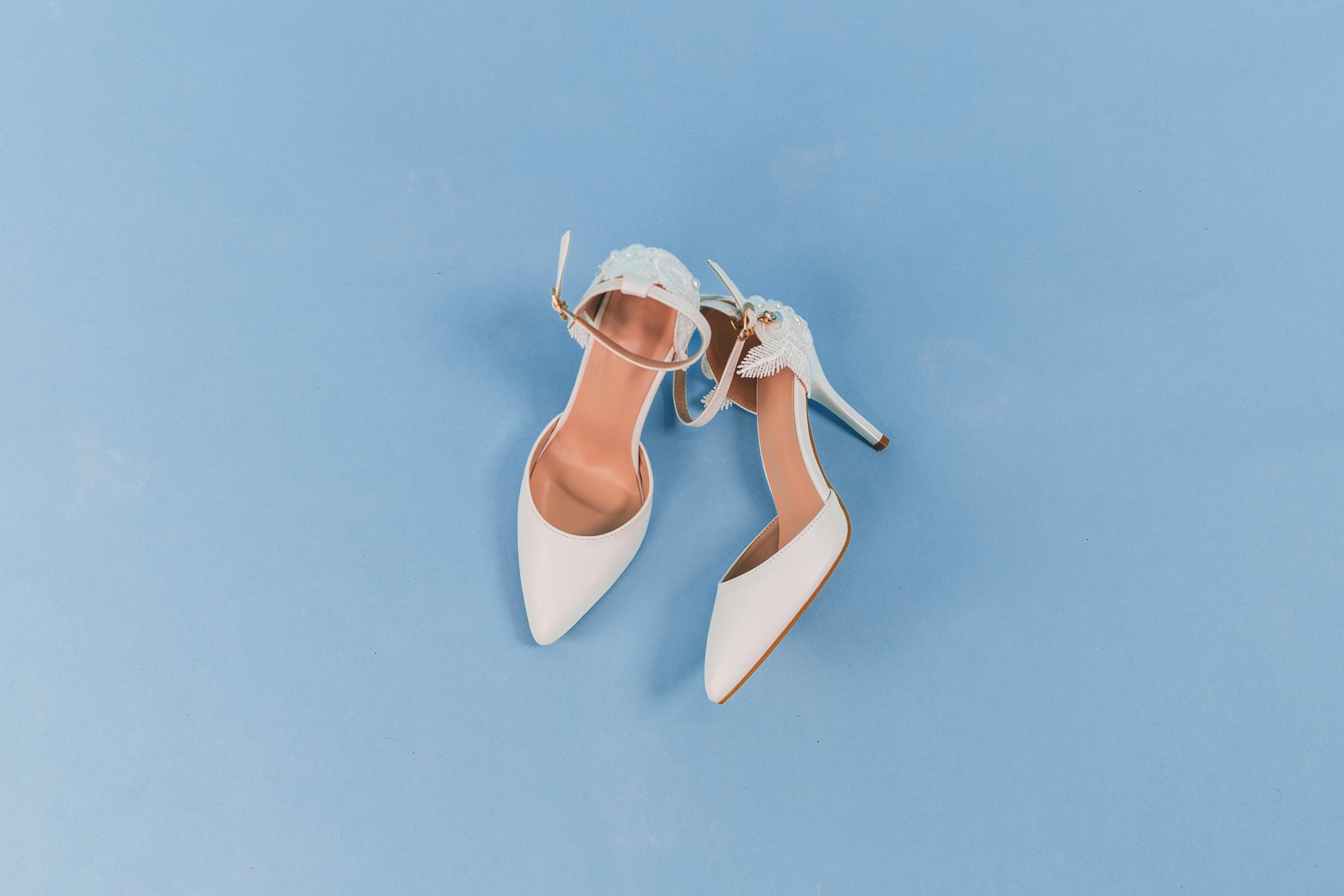 White high-heeled shoes on a light blue background