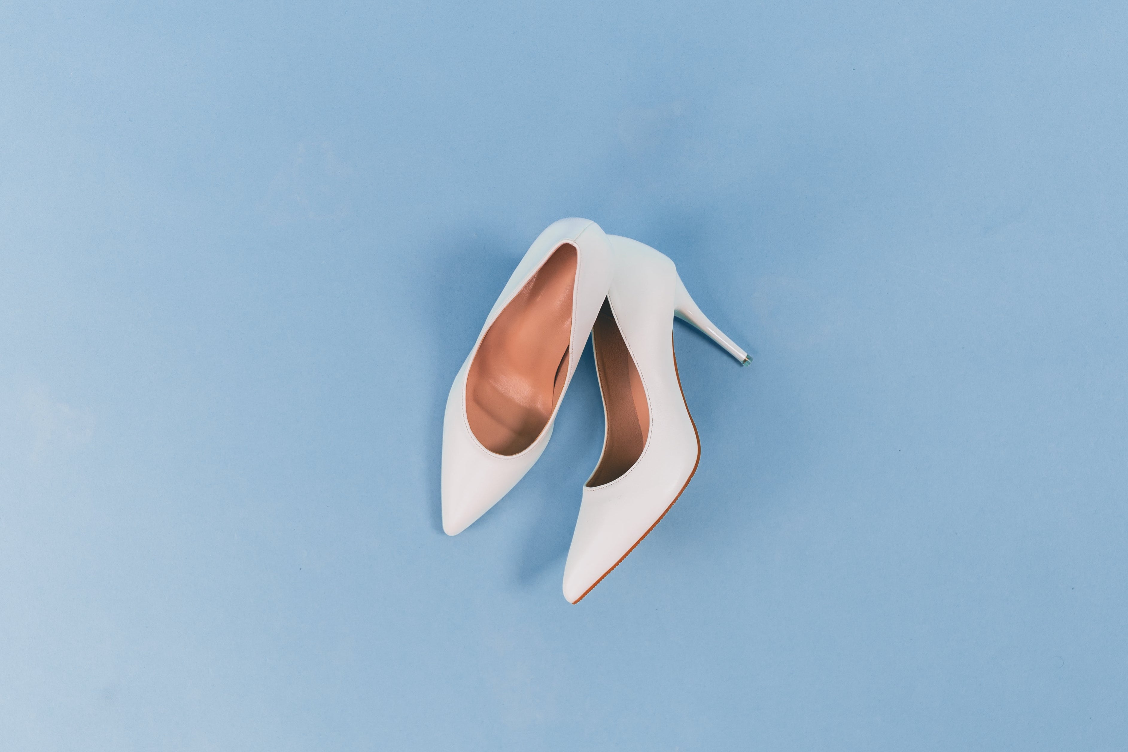White bridal shoes on a dusty blue background